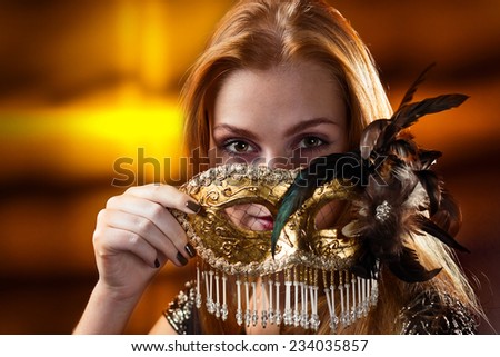 Young beautiful woman with gold venetian mask