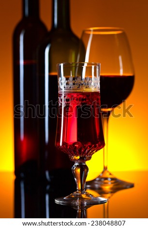 glasses and bottles with red wine on  mirror table