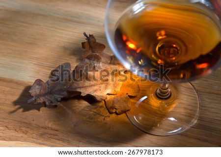 snifter with brandy and dried oak leaves