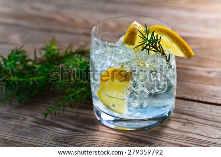gin and tonic with lemon and ice on wooden table