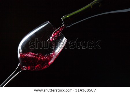 bottle and glass with red wine on  black background