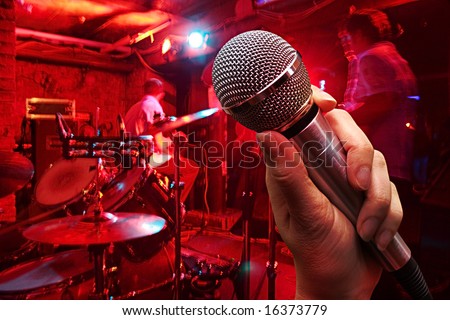 hand with microphone on a nightclub background