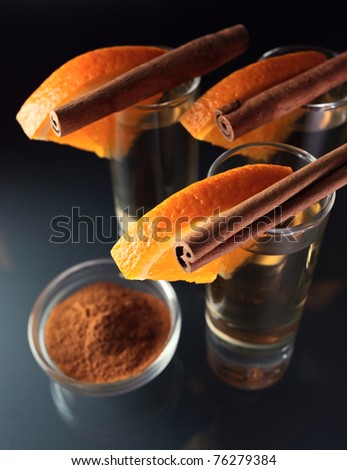 tequila with orange and cinnamon on a glass table.