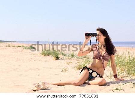 woman with field-glass on a beach.