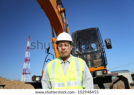 portrait construction worker on location site standing beside excavator