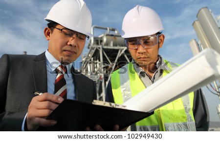 businessman and oil refinery engineer  discussing a new project with large oil refinery background