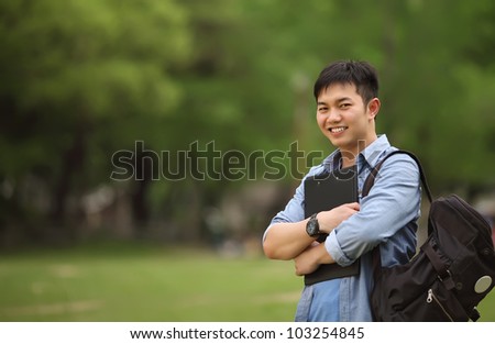 college student holding book on the park