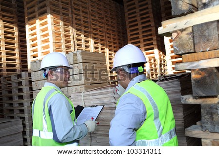 two workers talking beside on stacking pallet with holding notes