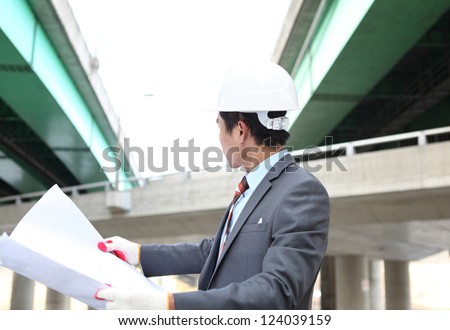 young architect  with blueprint on highway construction site