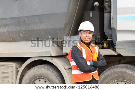 road construction worker standing beside the truck on location site
