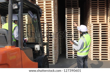 workers  at unloading works with forklift loader in warehouse