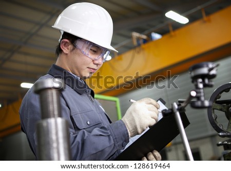 Mechanical technician writing on notepad in the factory