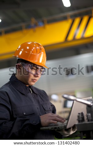 Technician working in factory using laptop