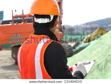 portrait construction worker in front of excavator checking plan