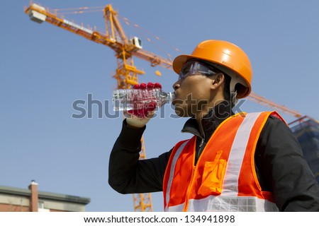 Engineer with safety vest drinking water under construction
