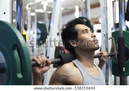 Man gym workout, using a squat machine at fitness club