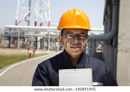 Chemical industrial engineer holding a notepad  with oil refinery background