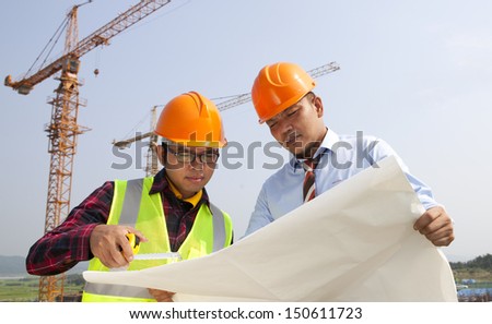 Manager and builder on the jobs site, discussion looking blueprint under new building construction