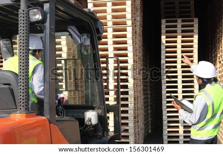 warehouse workers team at unloading works with forklift loader