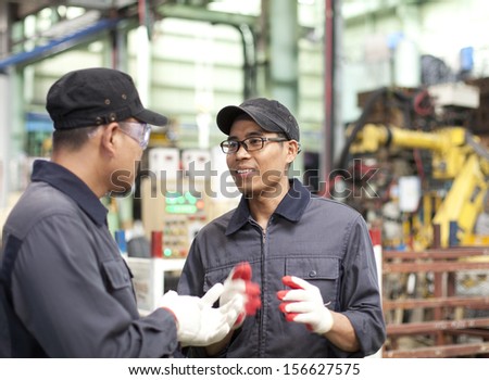 Two workers in a factory discussing how to work in factory