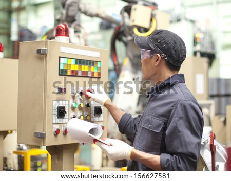 Manufacturing worker operating a robot machine with a control panel