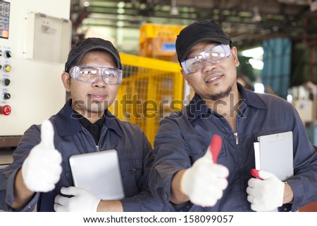 Two workers standing with show giving thumbs up