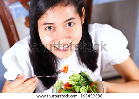 Woman eating salad. Portrait of beautiful smiling and happy mixed asian woman enjoying a healthy salad