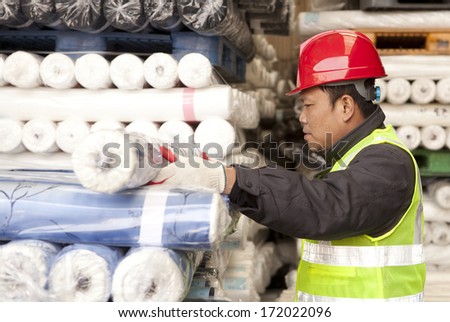 Textile factory worker arranging fabric in warehouse