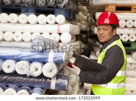 Textile factory foreman checking raw material fabrics in warehouse