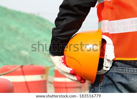 Industrial construction safety work concept of man worker holding hardhat on location site
