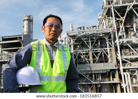 Chemical industrial  engineer with safety vest standing front of large oil industry