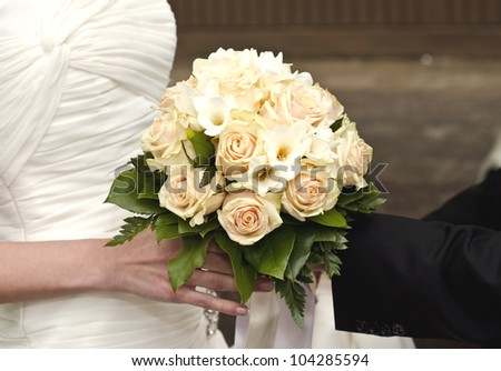 Image of wedding bouquet in hands of the bride and groom