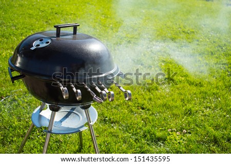image of kettle barbecue grill with cover on grass