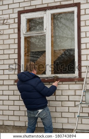 Image of man in winter jacket trying to fix the window