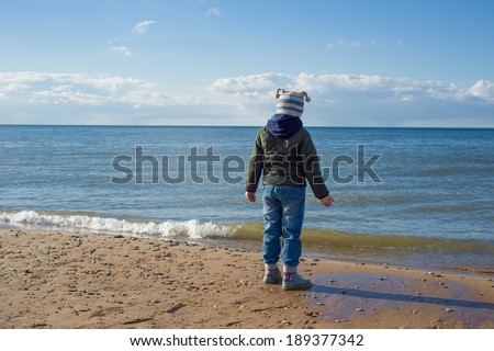 Image of Small kid standing on the beach and dreaming about summer