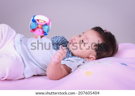 A child lying on the bed with the toy in his hand.