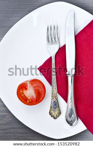Silverware and a tomato on a plate