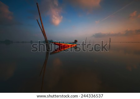 Sunrise scene with fisherman boat on the beach (soft focus, shallow DOF, slight motion blur)
