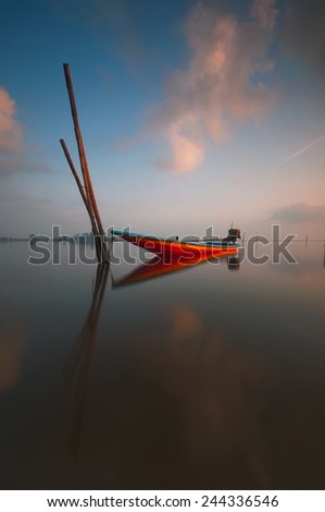 Sunrise scene with fisherman boat on the beach (soft focus, shallow DOF, slight motion blur)
