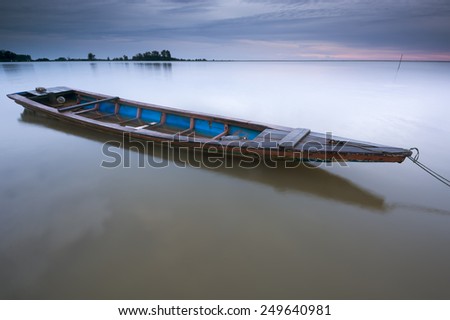 Wooden boat at the beach during dawn times. Slight motion blur on the boat due to long exposure.