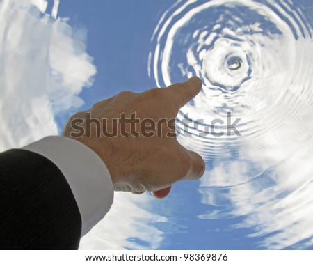 Business man\'s hand pointing to sky causing sky to ripple