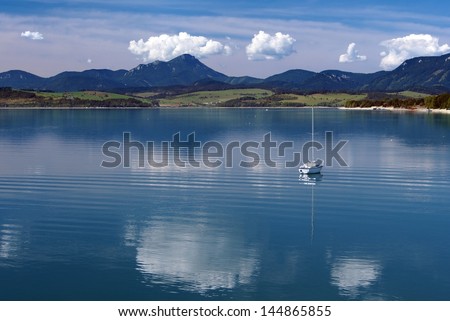 Summer view of Liptovska Mara lake with small yacht and Choc Mountain Range in background. Liptovska Mara lake is popular summer holiday destination for Slovak and also for foreign tourists.