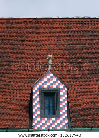 Colorful dormer window on red tiled roof.