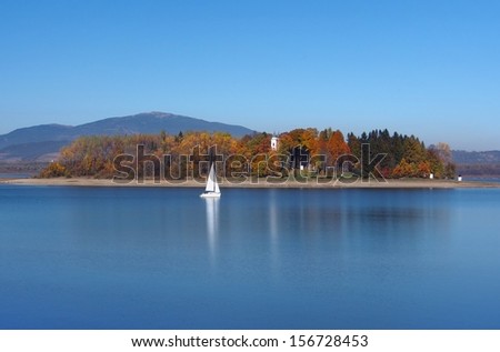 Orava reservoir with yacht and Slanica Island, also called Island of art. Slanica Island is popular destination for visitors because it hosts permanent expositions showcasing traditional folk art.