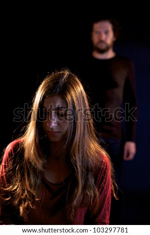 Sad woman oppressed by dark man behind her
