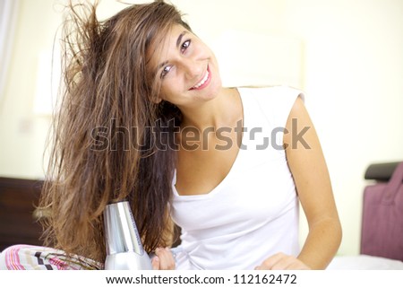 Cute female model with wet hair drying it in bed