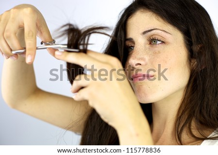 Gorgeous female model cutting her long beautiful silky hair