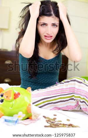 Sad depressed young woman holding hair few money left in piggy bank