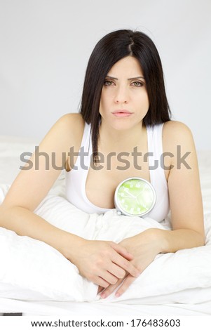 Beautiful woman with heart problem with alarm clock showing end of time