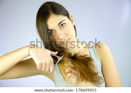 Woman looking with scissors in hand and holding long hair to be cut